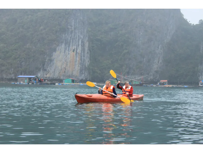 Turistas haciendo kayak entre aldeas flotantes en la Bahía de Halong, Vietnam