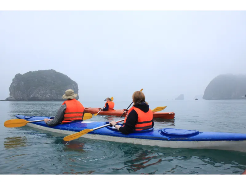 Grupo de personas remando en kayak por aguas tranquilas de la Bahía de Halong