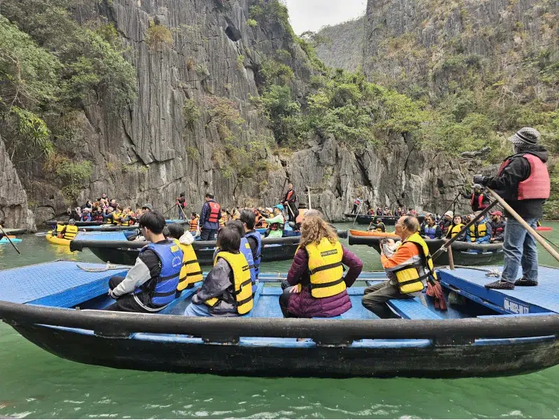 Excursión guiada en barca redonda por un cañón de piedra en la Bahía de Halong