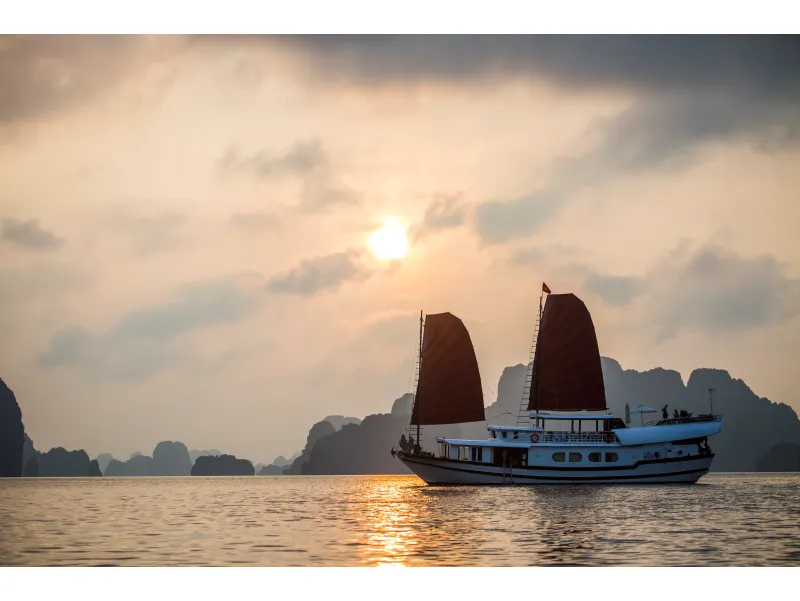 Velero navegando al atardecer en la Bahía de Halong, Vietnam