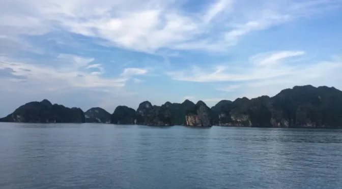 Formaciones rocosas de la Bahía de Lan Ha bajo cielo azul y aguas tranquilas en Vietnam