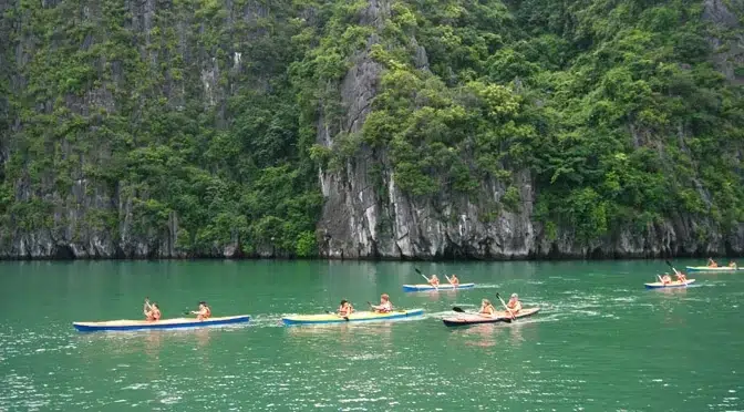 Turistas practicando kayak entre acantilados verdes en la Bahía de Lan Ha