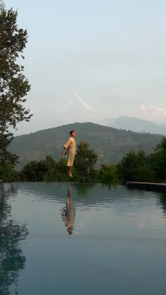 Hombre frente a piscina infinita con vistas al Himalaya en un viaje a medida a Nepal.