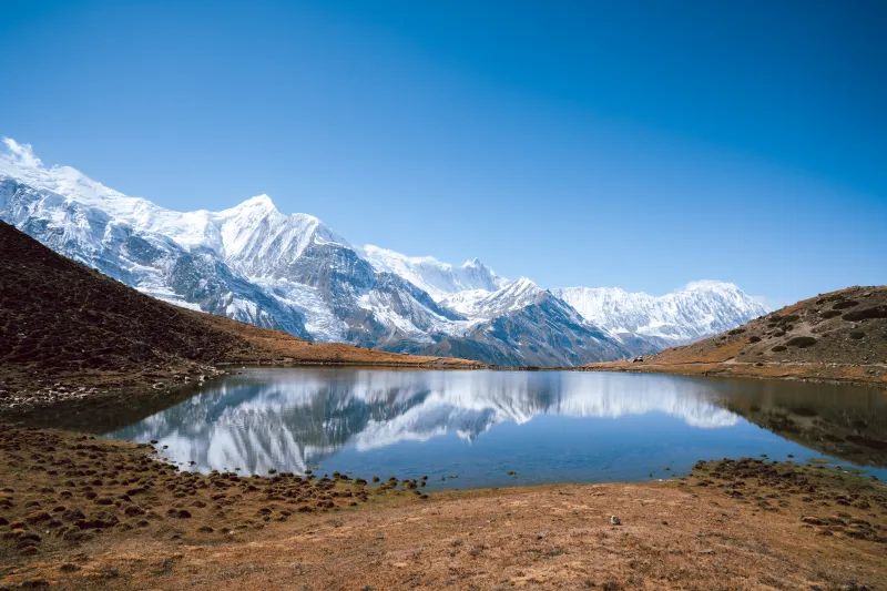 Lago helado en el Himalaya con reflejo de montañas en trekking por Annapurna.