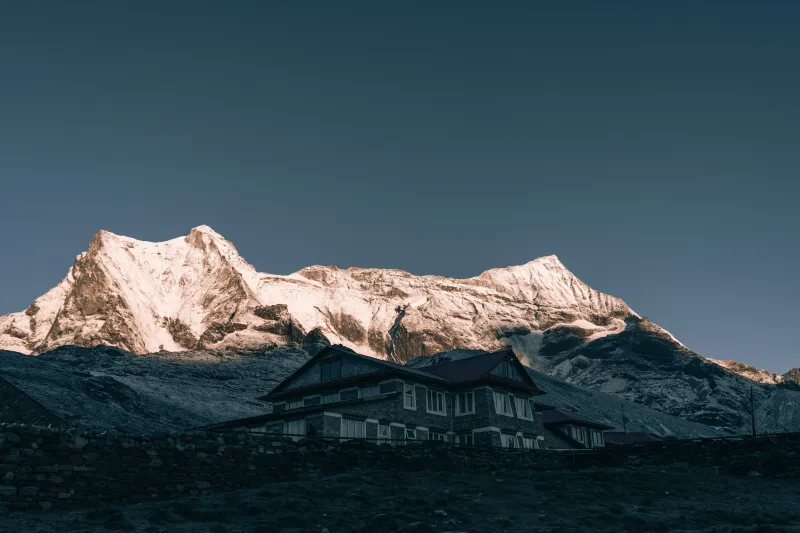 Lodge de montaña con fondo del Annapurna iluminado al amanecer en trekking por Nepal.