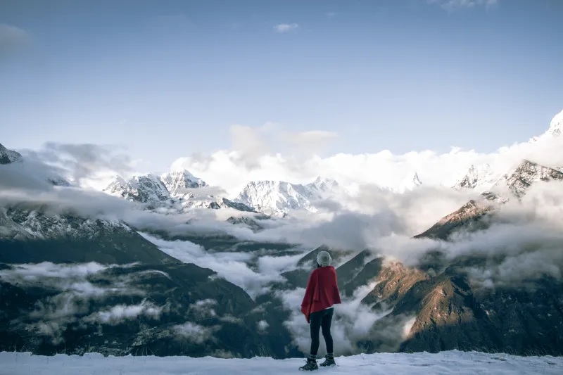 Mujer contemplando el Himalaya entre nubes en un trekking de altura en Nepal.