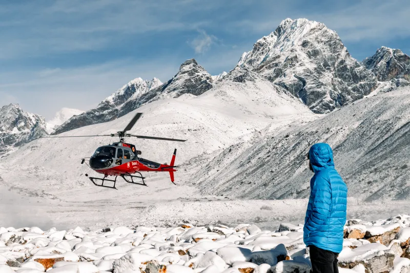 Helicóptero rojo sobrevolando el Himalaya en un viaje exclusivo a Nepal.