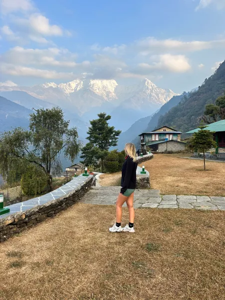Viajera contemplando el Himalaya desde lodge tradicional en trekking por Nepal.