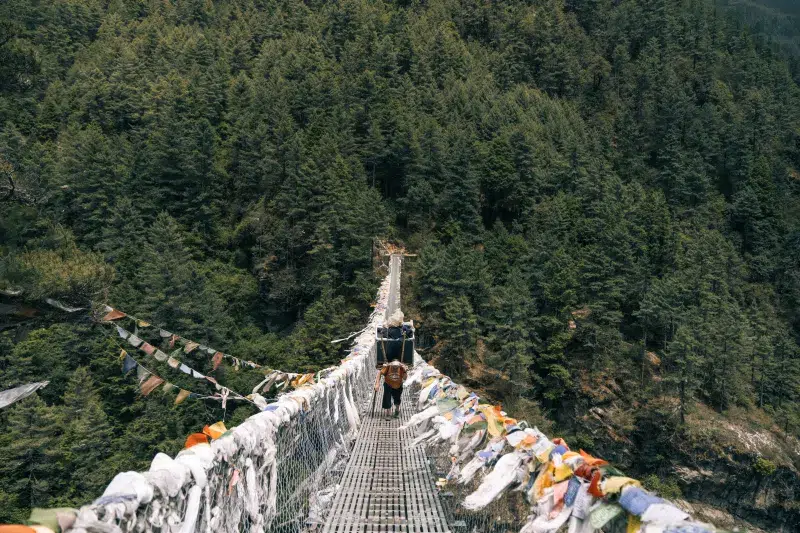 Puente colgante con banderas de oración en ruta hacia el Everest, Nepal.