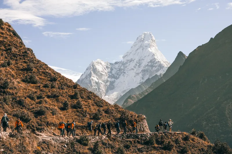 Grupo de senderistas ascendiendo con la montaña Ama Dablam de fondo en Nepal.