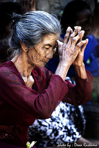 mujer mayor en acto de oración tradicional balinesa
